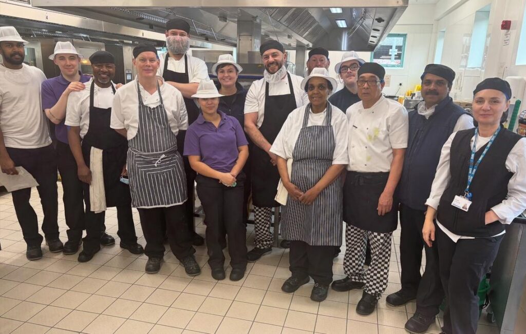 Members of the catering team, large group standing in hospital kitchen