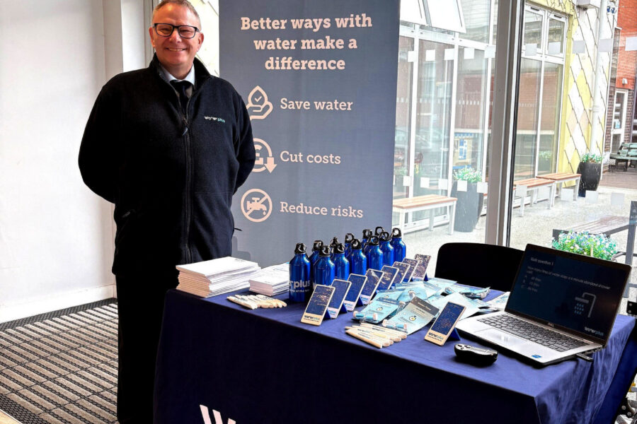 Man standing with 'water Plus' sign and promotional items in hospital restaurant